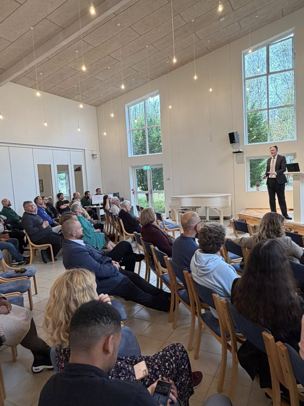 Bradley Burnham presenting to a full congregation in a bright, modern church sanctuary